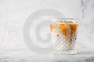 Glass with cold brew coffee and milk isolated on bright marble background. Overhead view, copy space. Advertising for cafe menu.