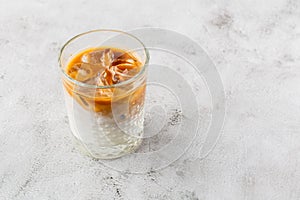 Glass with cold brew coffee and milk isolated on bright marble background. Overhead view, copy space. Advertising for cafe menu.