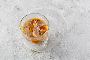 Glass with cold brew coffee and milk isolated on bright marble background. Overhead view, copy space. Advertising for cafe menu.