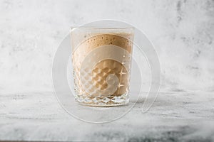 Glass with cold brew coffee and milk isolated on bright marble background. Overhead view, copy space. Advertising for cafe menu.