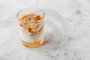 Glass with cold brew coffee and milk isolated on bright marble background. Overhead view, copy space. Advertising for cafe menu.