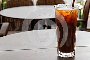 A glass of cold brew iced coffee, cola or cocktail on a cafe table