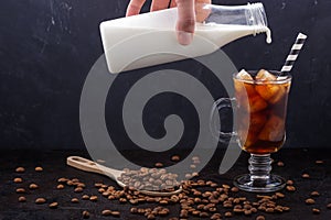 In a glass of cold brewing coffee poured milk from a bottle