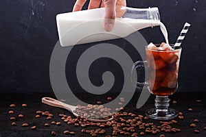 In a glass of cold brewing coffee poured milk from a bottle