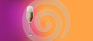 Glass with cold champagne with bubbles isolated over gradient purple and orange color background in neon. Concept of