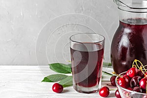 Glass of cold cherry juice with a jug and fresh berries on white background. Refreshment summer drink