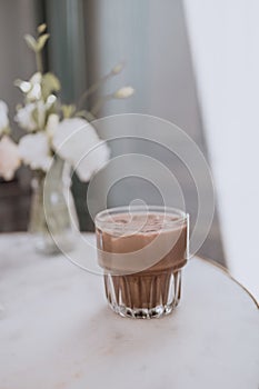 Glass of cold chocolate milk drink on a white marble table.