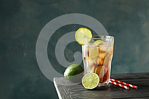 Glass of cold cola with citrus and ice on wooden table