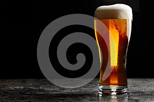 Glass of cold craft light beer on dark background