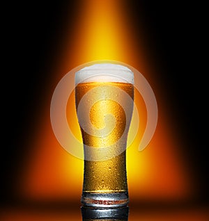 Glass of cold craft light beer on dark background.