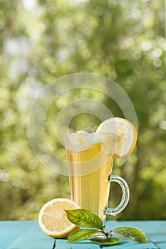 Glass of cold drink with ice and lemon on table