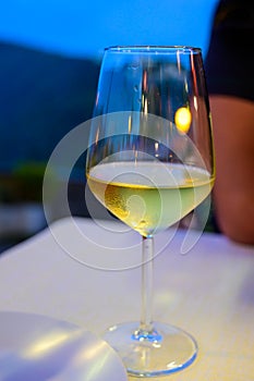 Glass of cold dry white wine served outdoor in cafe at night in Italy