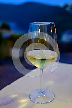 Glass of cold dry white wine served outdoor in cafe at night in Italy