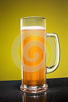 Glass of cold frothy lager beer on an old wooden table