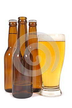 Glass of cold lager beer isolated on white background with brown bottles