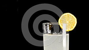 A glass of cold lemonade with a piece of yellow lemon