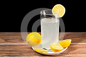 A glass of cold lemonade with a piece of yellow lemon