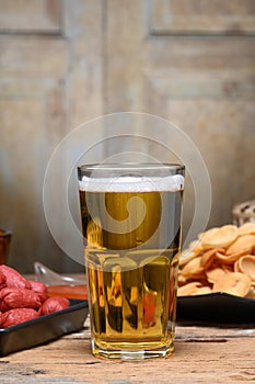 Glass of cold light beer with snacks