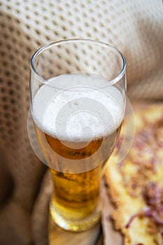 A glass of cold light beer. Very tasty and delicious pizza with tuna, red onion, cheese. Thin Italian pastry. Close-up, top view