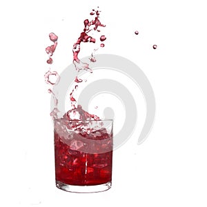 Glass of cold red fruity drink with water splash and ice cubes.