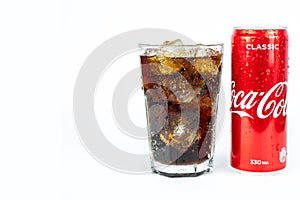 Glass of cold refreshing coca cola soda with ice, metal can of coca cola classic, isolated on white