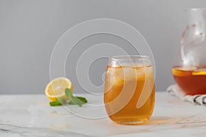 A glass of cold tea, ice cubes, lemon slices and a sprig of mint. Cooling summer drinks.