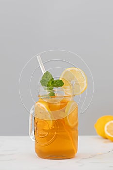 A glass of cold tea, ice cubes, lemon slices and a sprig of mint. Cooling summer drinks.