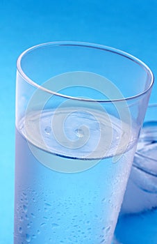 Glass of cold water in front of blue background