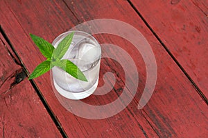 Glass of cold water with ice and mint on wooden table