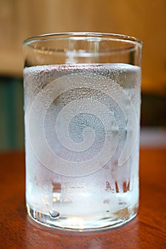 Glass of cold water isolated on wooden table