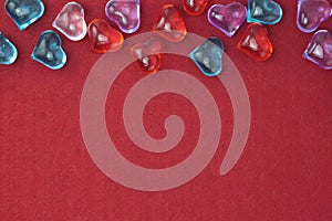 Glass colored hearts on a red background. Valentines day. Place for text.