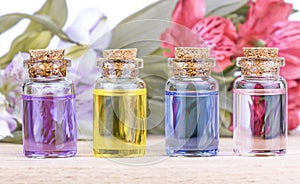 Glass colorful bottles aroma oil and flowers on wooden table