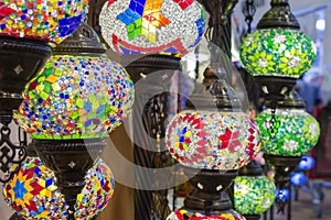 Glass, colorful, traditional, decorative Turkish lamps hang on the ceiling in the store