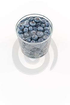 glass container with water and fresh blueberries against white background