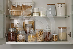 Glass containers with different breakfast cereals and other products on shelves