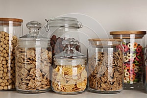 Glass containers with different breakfast cereals on shelf