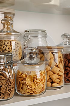 Glass containers with different breakfast cereals on shelf