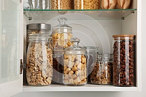 Glass containers with different breakfast cereals on shelf