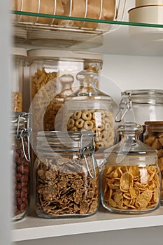 Glass containers with different breakfast cereals on shelf