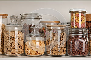 Glass containers with different breakfast cereals on shelf