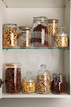 Glass containers with different breakfast cereals on shelves