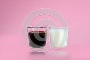 Glass of cool fresh milk, black coffee with reflection on pink background. Beverage in morning concept