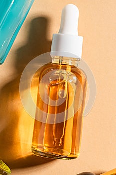 glass cosmetic bottle with a dropper on a beige background. Natural cosmetics concept, natural essential oil and skin care