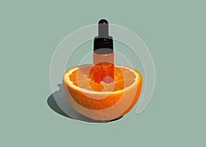 Glass cosmetic dropper bottle with orange oil or serum in half ripe orange fruit. Anti-aging skin care with vitamin C.