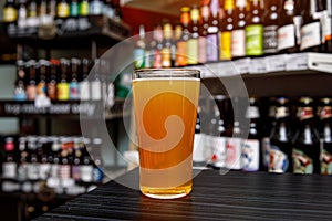 Glass of craft beer at the bar. Assortment of bottles on a blurred background.