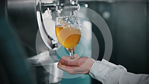 glass with craft light beer in hand of man inside workshop of modern brewery