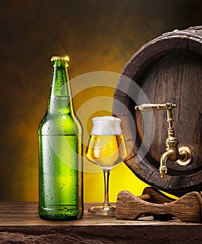 Glass of craft pale lager beer, beer bottle and wooden cask on the wooden table in the cellar