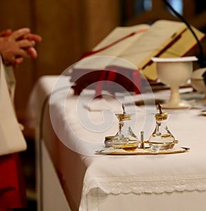 glass cruets above the altar and the priest reading the Bible du