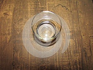 A glass of crystal clear drinking water on top of a wooden table