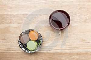 Glass cup of black tea and colorful macarons
